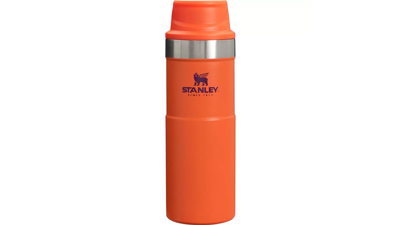 Orange travel mug placed against white background.