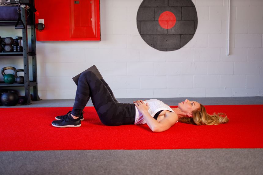 Set up a bridge squeeze by placing a yoga block between your knees while lying on your back with knees bent and feet flat on the floor.