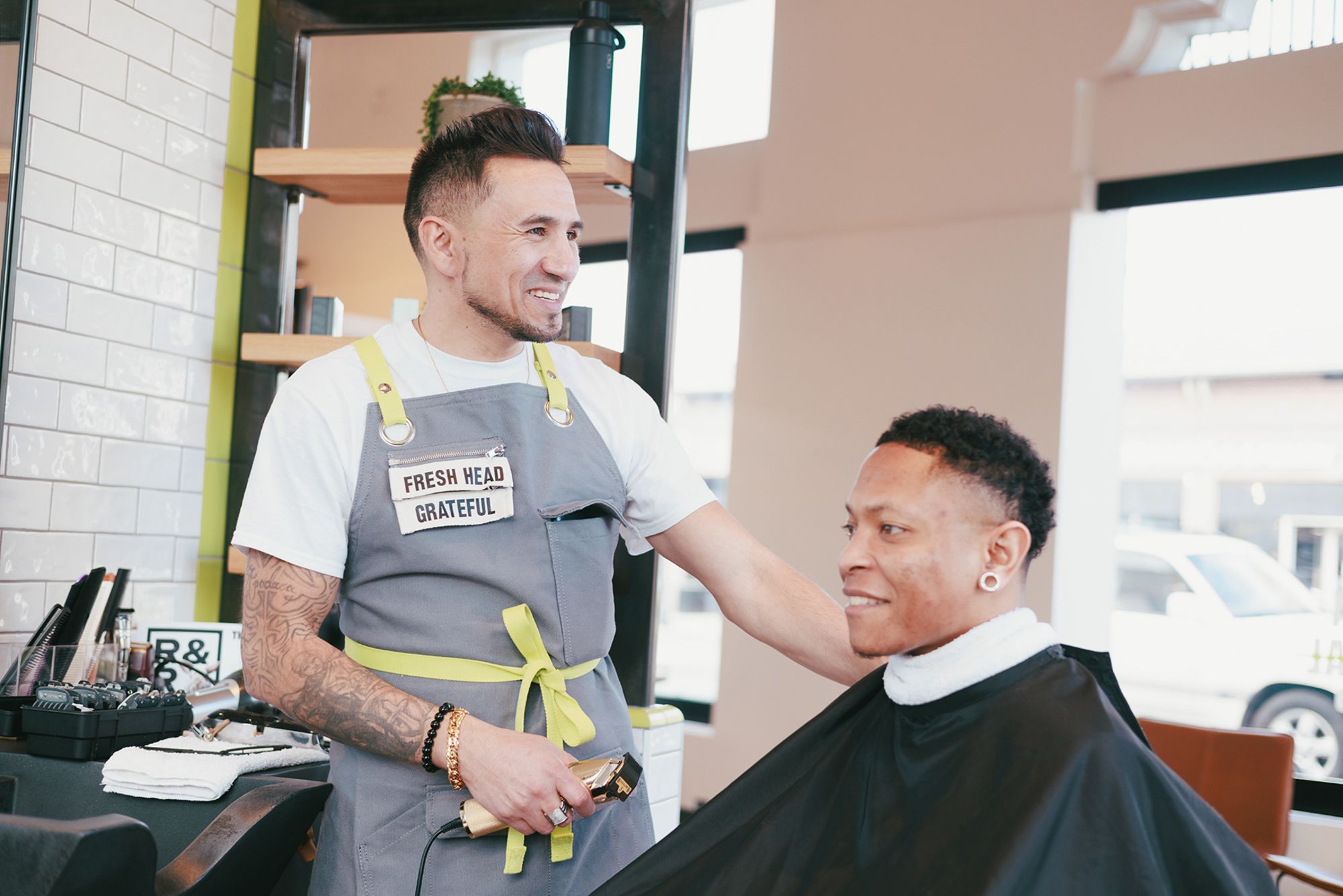 At R&R Head Labs in Denver, Colorado, barbers' aprons feature space for an interchangeable tag featuring a word that best describes their intention or vibe of the day. Pictured above, skilled apprentice Stephen Apodaca's says "grateful."