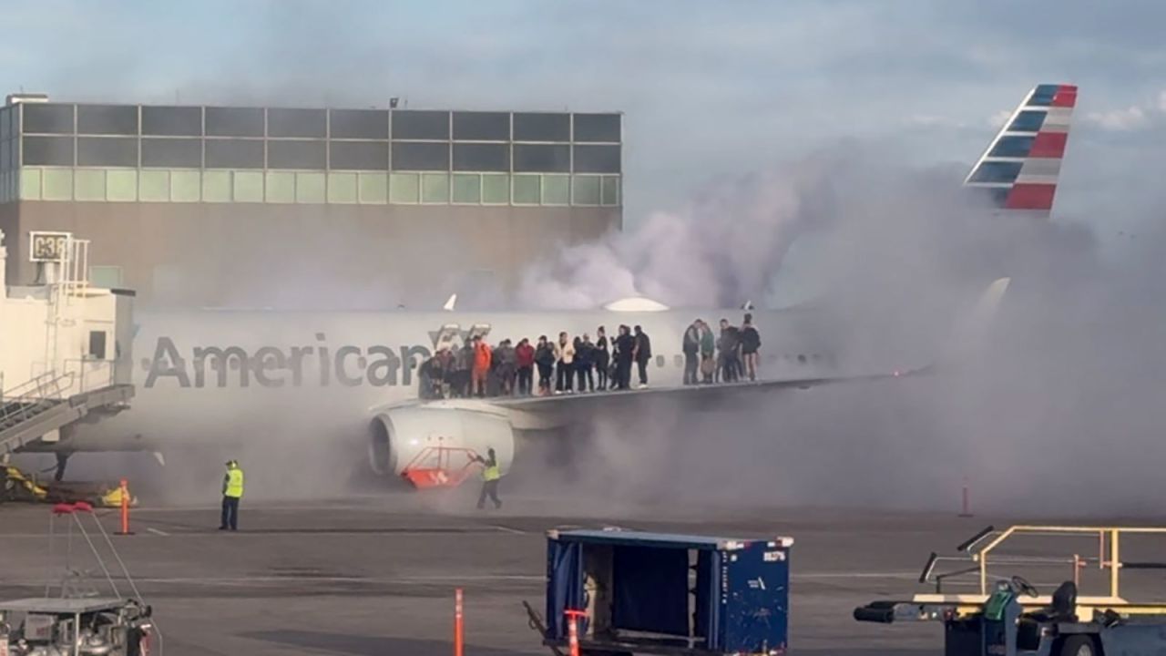 Airplane passengers are seen exiting the plane and standing on the wing as smoke rises around them at the Denver airport on Thursday.