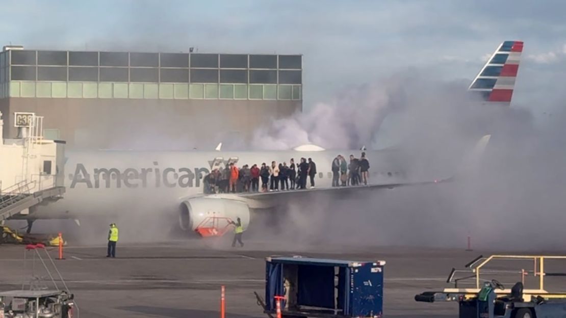 Airplane passengers are seen exiting the plane and standing on the wing as smoke rises around them at the Denver airport on Thursday.