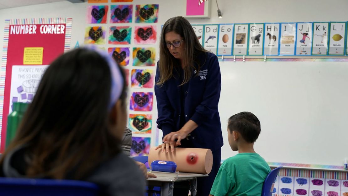 Kate Carleton, center, teaches children at a California elementary school how to stop a wound from bleeding out.