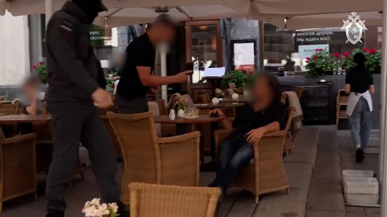 An image taken from a video released by the Russian Investigative Committee shows the man being arrested by security personnel at a cafe in Moscow. The video was blurred by the source.