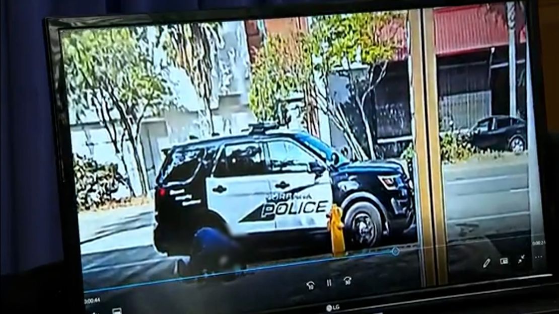 In this surveillance video released by Los Angeles City Council President Paul Krekorian, a homeless man crouches on the ground in front of a police vehicle. CNN has blurred parts of the footage to protect the person's identity.