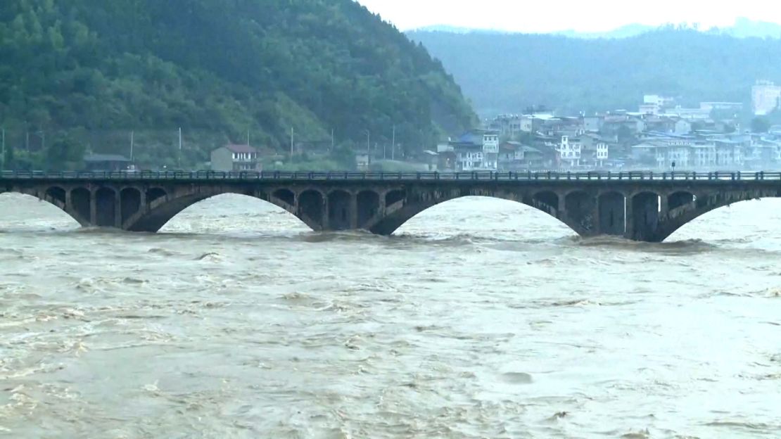 Floodwaters climbing up the pillars of a bridge.