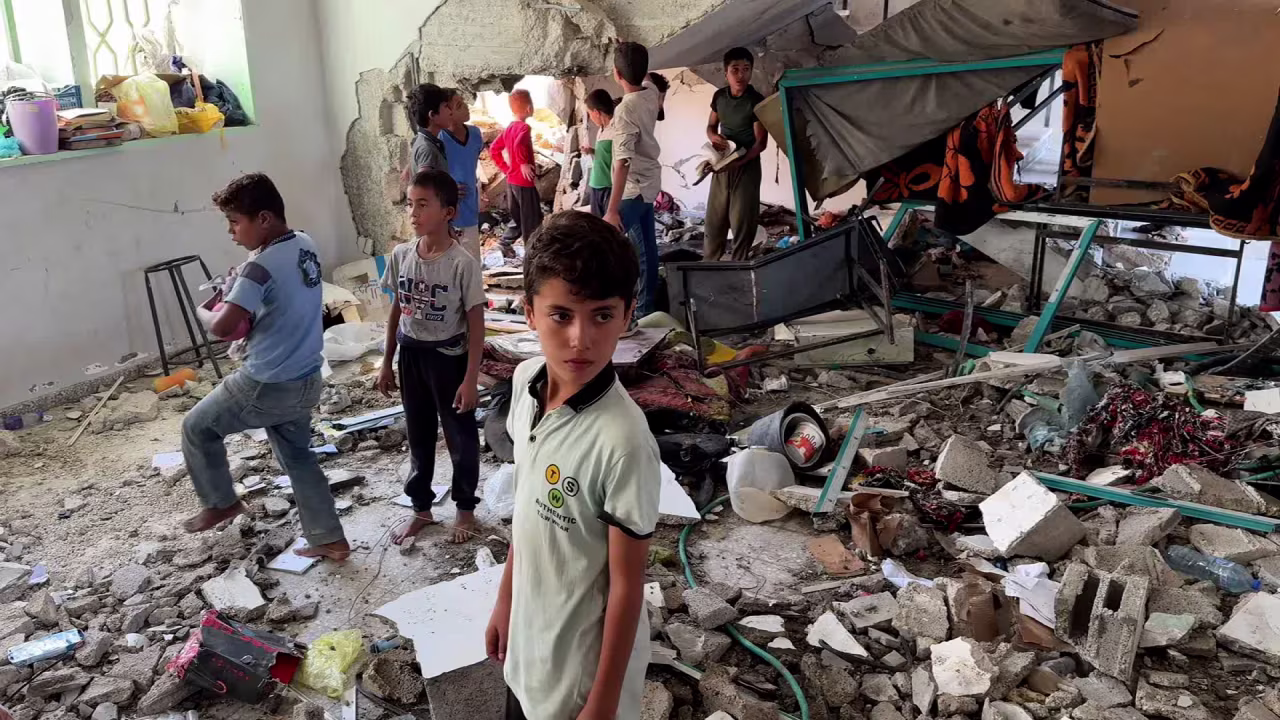 Children look through debris and recover items from the school in Deir al-Balah, Gaza.