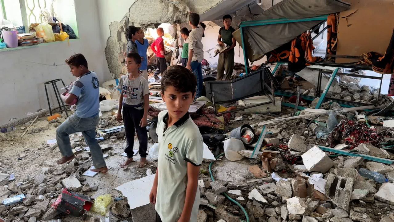 Children look through debris and recover items from the school in Deir al-Balah, Gaza.