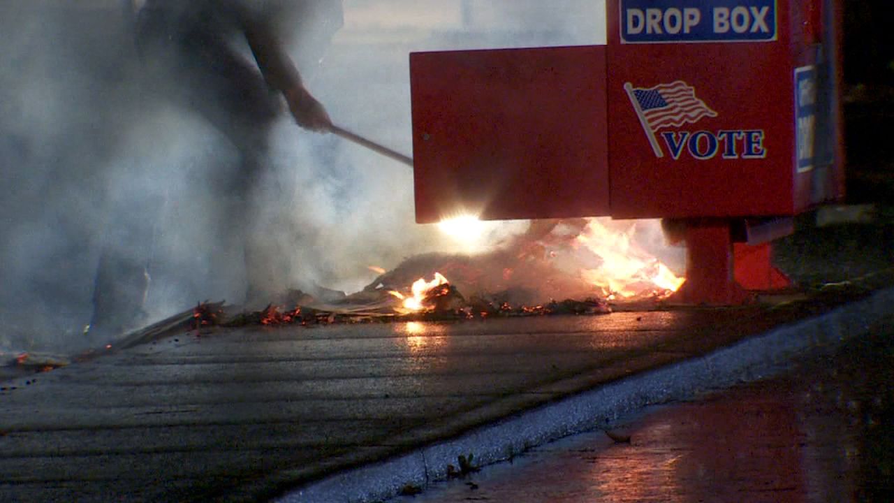 Police work to put out a fire at a ballot box in Vancouver, Washington, on Monday.