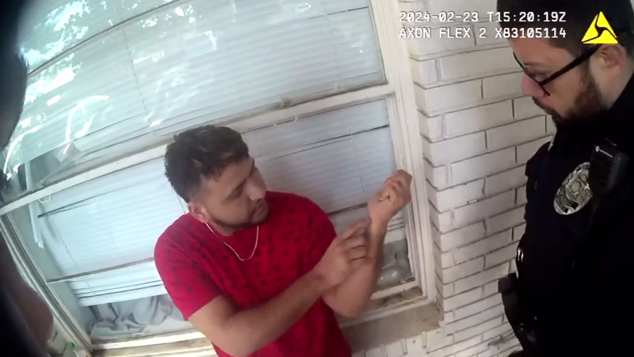A screengrab from police body camera footage shows Jose Ibarra pointing to his wrist while being questioned by police the day after Laken Riley was killed.