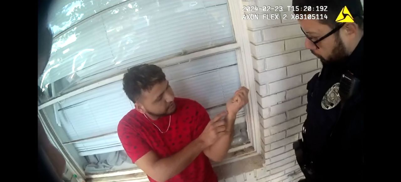 A screengrab from police body camera footage shows Jose Ibarra pointing to his wrist while being questioned by police the day after Laken Riley was killed.