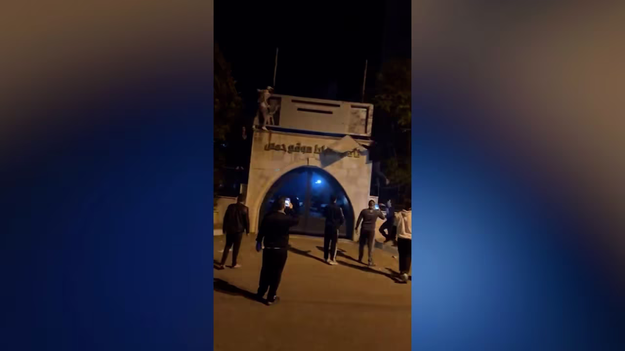 In this still from a video geolocated by CNN, Homs residents are seen tearing down posters of President Bashar al-Assad.