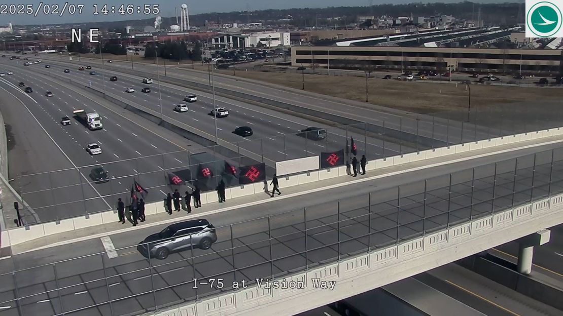 Demonstrators wearing all black and carrying large swastika-emblazoned Nazi flags stand along a highway overpass in Evendale, Ohio, on Friday.