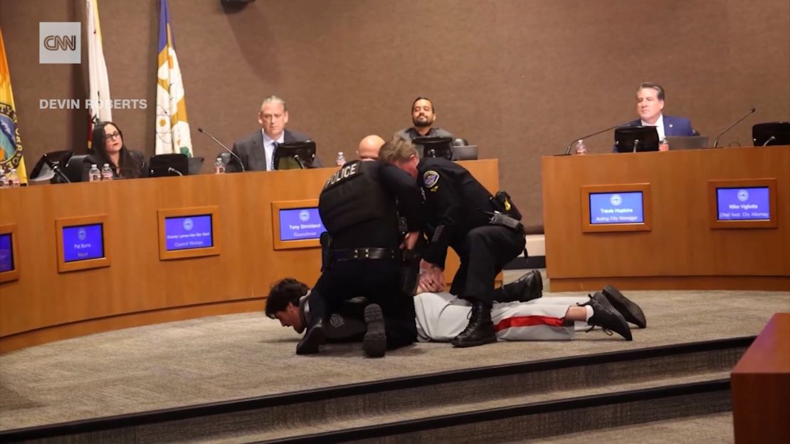 Kluwe is held down by police at the council meeting.