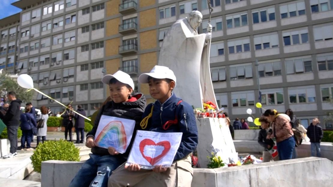 Children pose by the statue of John Paul II outside the Gemelli University Hospital where Pope Francis is hospitalised, in Rome on Sunday.