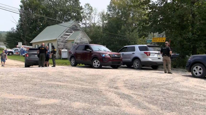 Police officers block the street leading to where two Pennsylvania state troopers were shot Thursday, near Thompson Township in Susquehanna County, Pennsylvania.