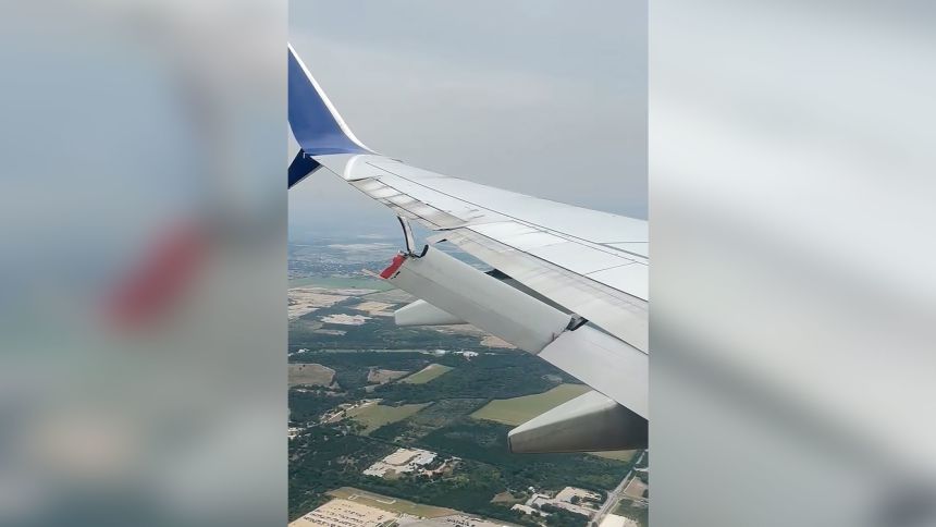 A still from a video taken aboard a Delta flight Tuesday, August 19, 2025, shows a flap dangling behind a wing of the plane.