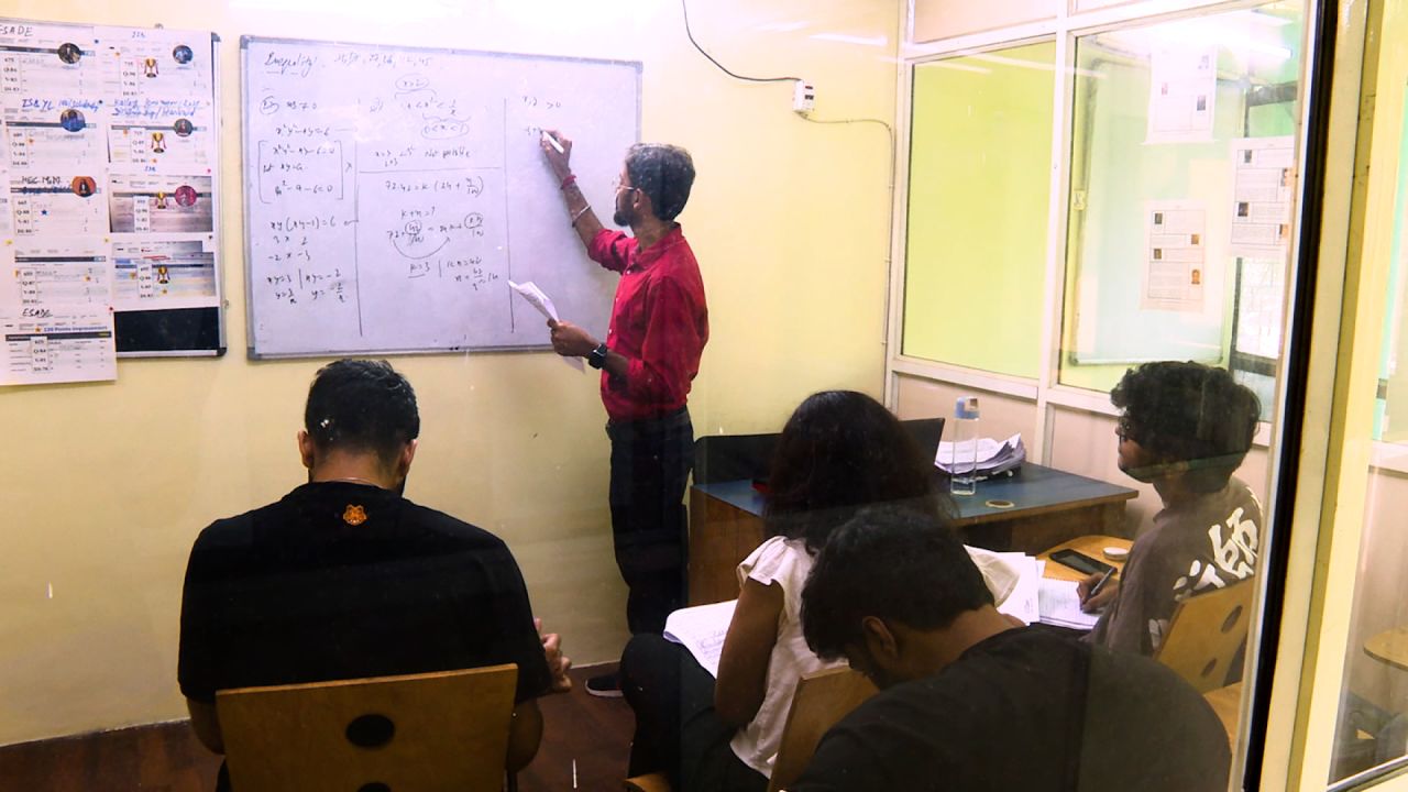 A teacher instructs students in a classroom in India.