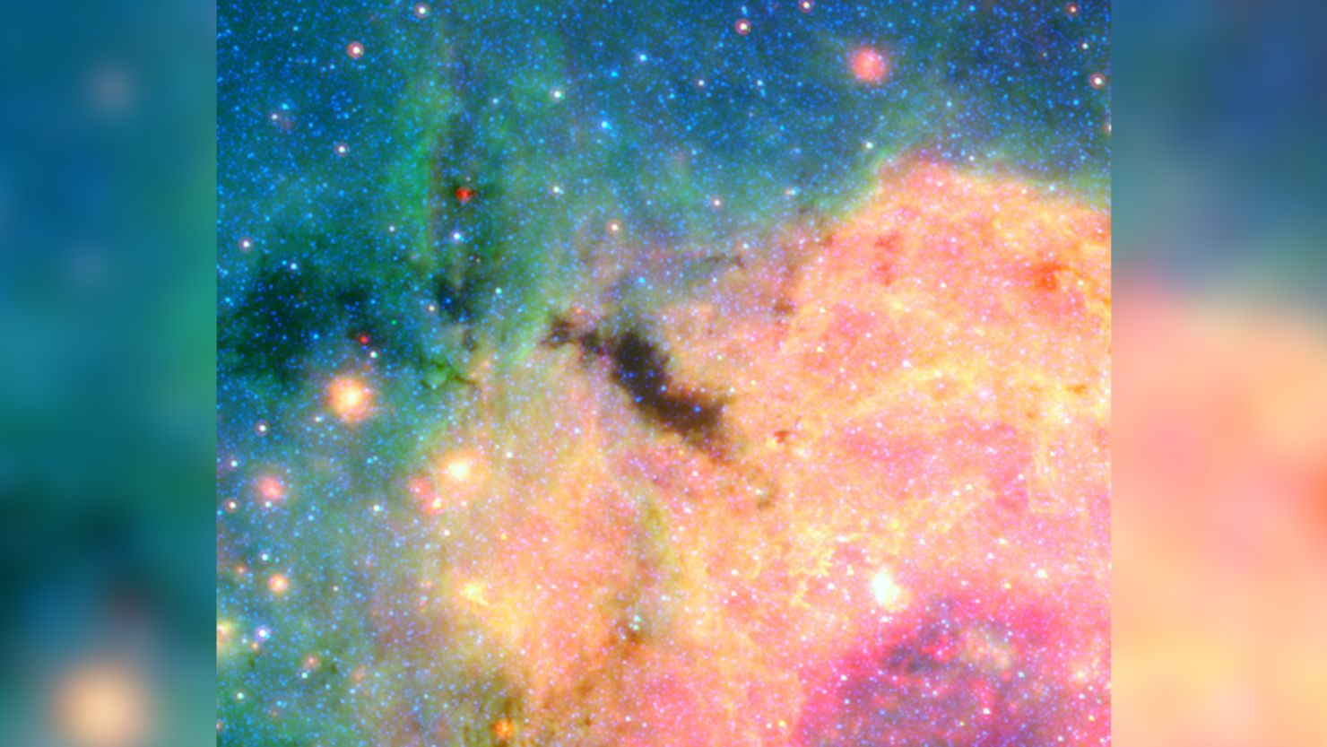 This view of the center of our galactic metropolis was captured by the Spitzer Space Telescope, offering an infrared view of the frenzied scene at the center of our Milky Way and revealing what lies behind the dust. "The Brick" is the dark blob at the center of the image, and the more advanced James Webb Space Telescope is offering researchers a closer look.