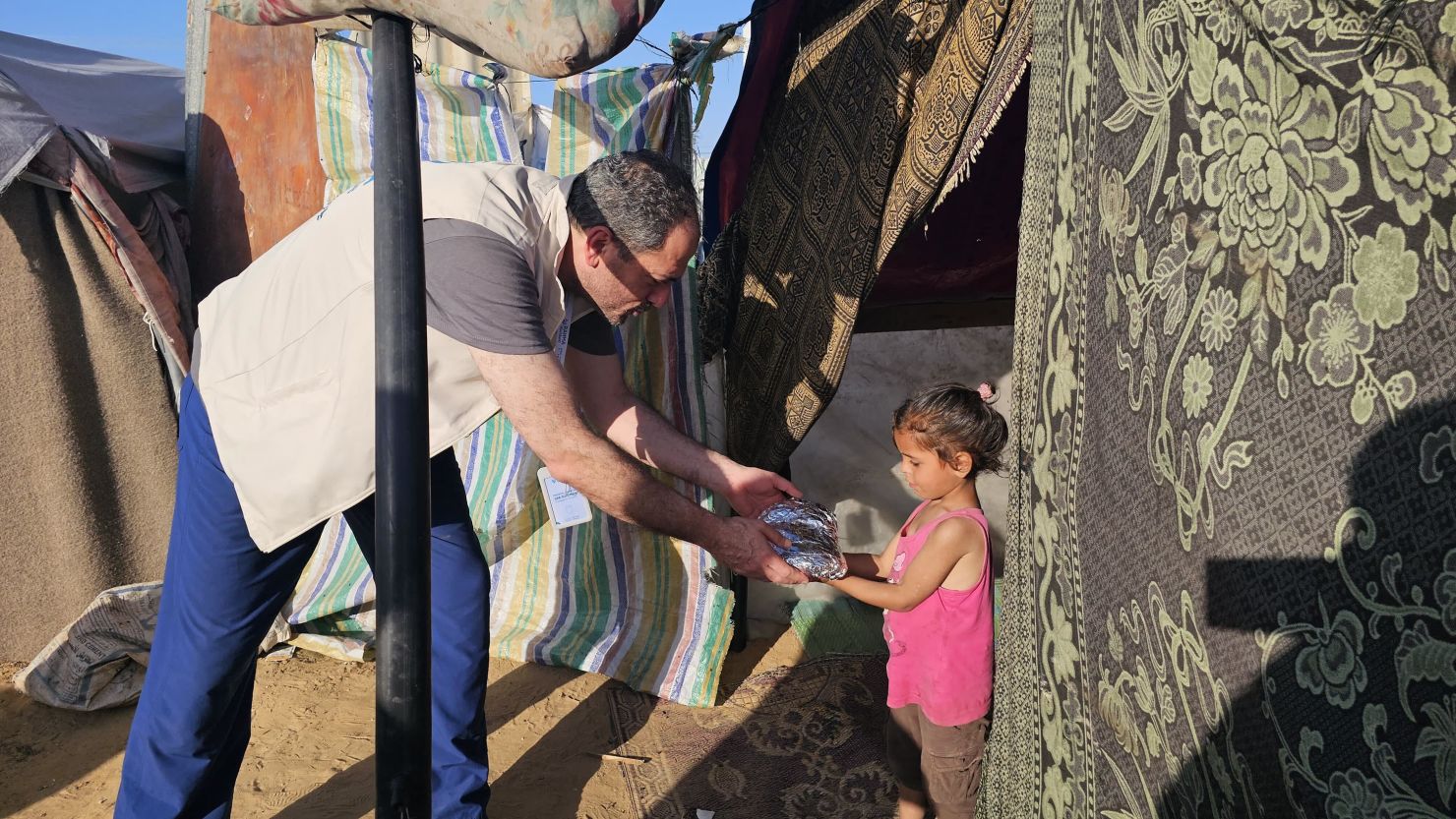 Palestinian-American orthopedic surgeon Jiab Suleiman distributes food to children living in a refugee camp in Khan Younis, in southern Gaza, in April.