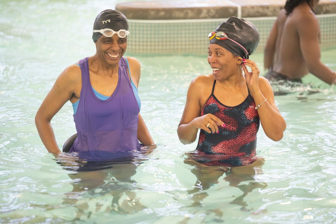 Jamie McDonald (right) takes a swim lesson with another parent, Reggae Anwisye, during their children’s practice at the YMCA’s O’Fallon Park Rec Complex on March 18.