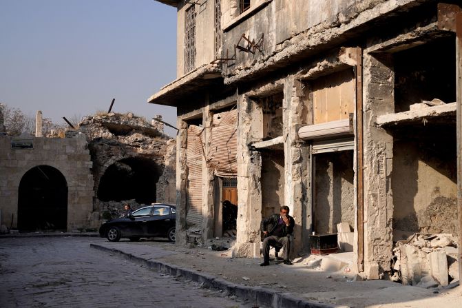 A man sits outside a damaged building in Aleppo on December 9.