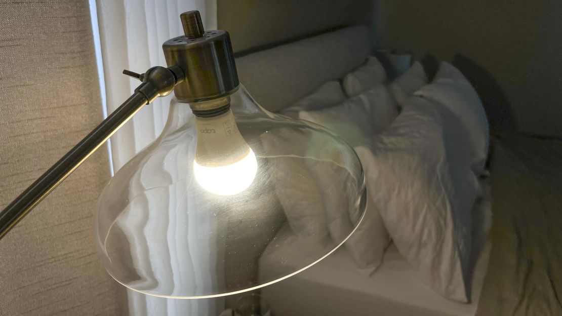 A Tapo smart bulb in a bedroom lamp with a glass shade.