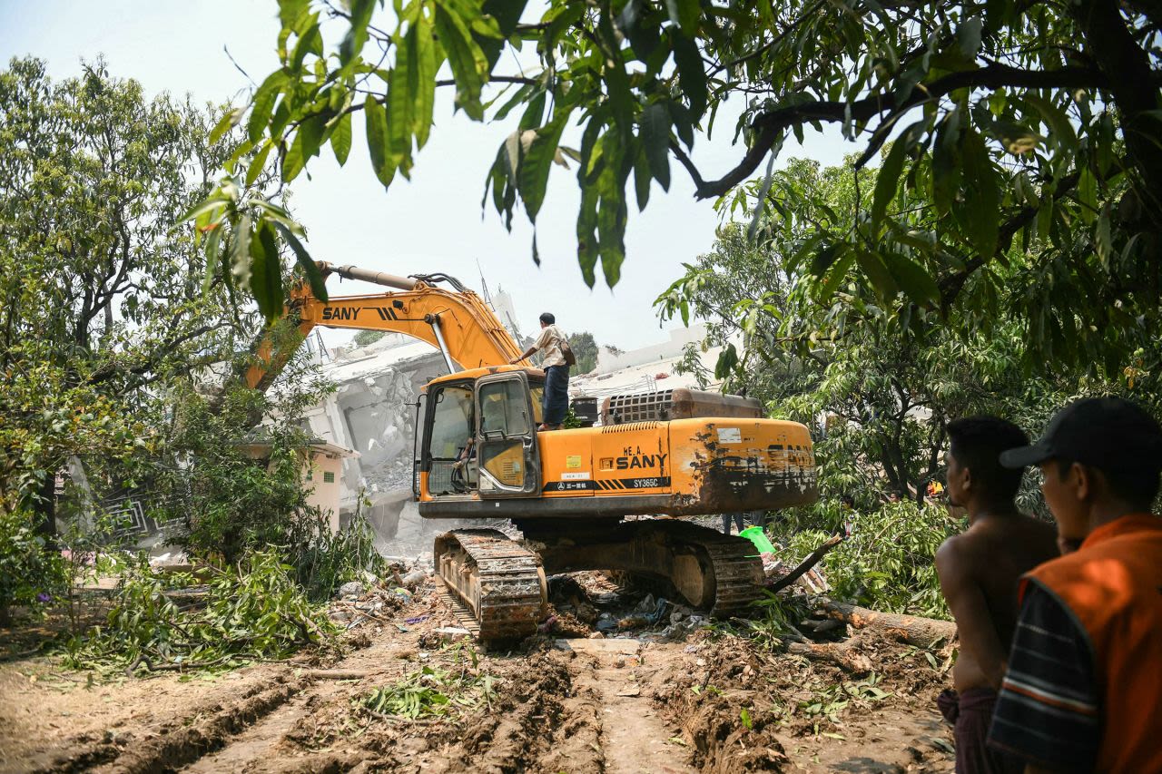 Equipos de construcción son utilizados para excavar entre los escombros, mientras personas buscan sobrevivientes en un edificio dañado en Mandalay el sábado 29 de marzo.