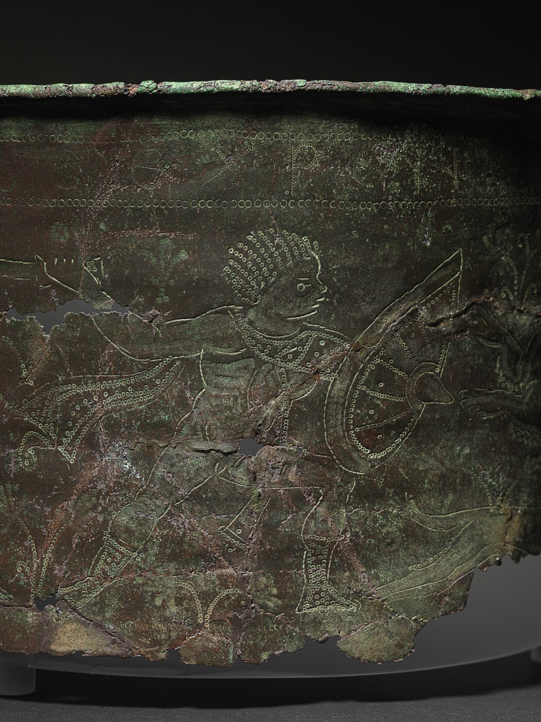 Fragments of the Bromeswell bucket found during previous excavations depict a North African hunting scene. The incomplete artifact is on display in the High Hall exhibition at Sutton Hoo in Suffolk, England.