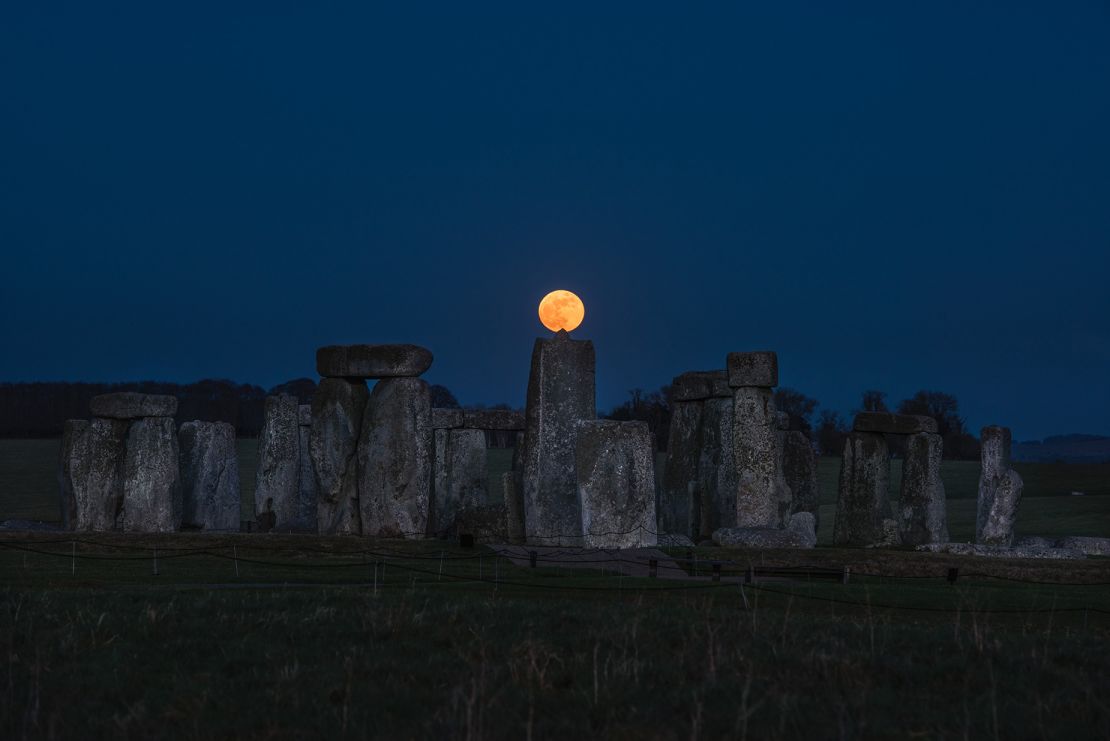 The moon is seen above the megaliths that make up Stonehenge, located on the Salisbury Plain in the county of Wiltshire in England.