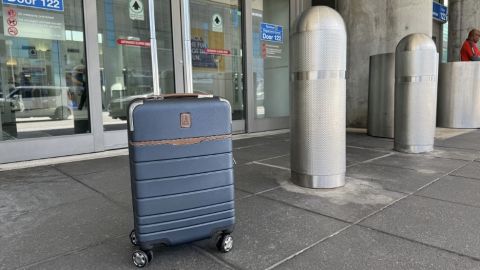 The Travelpro? x Travel + Leisure? Carry-On Spinner in front of airport