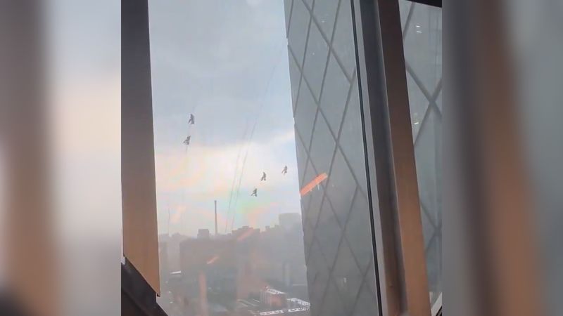 Window washers dangle from iconic Beijing tower during intense storms