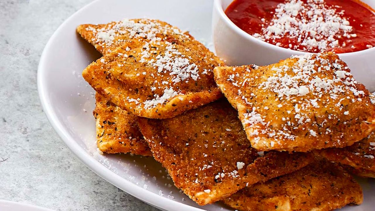 toasted ravioli on a white plate with dipping sauce