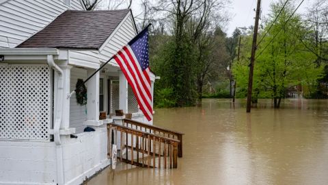 Una bandera estadounidense ondea en el porche de una casa en un vecindario inundado el domingo, en Frankfort, Kentucky.