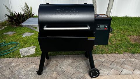 A Traeger Ironwood 885 pellet grill set up on a patio in front of a small lawn area