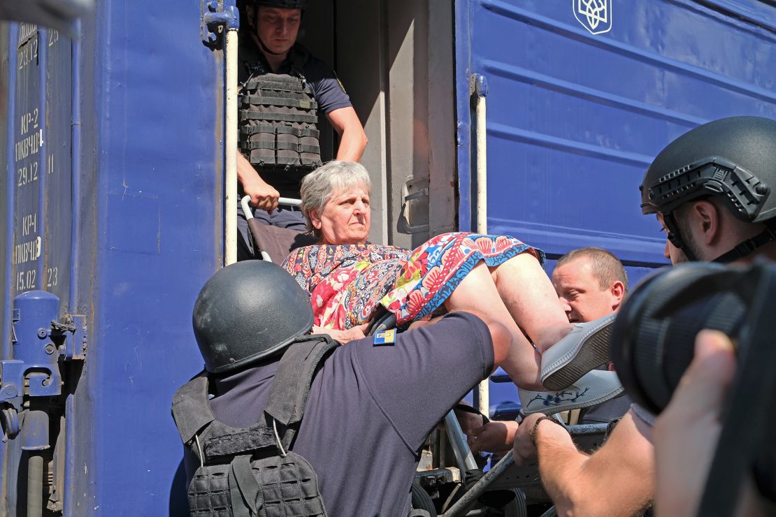 Liubov, 70, is being lifted onto the evacuation train by Pokrovsk police.