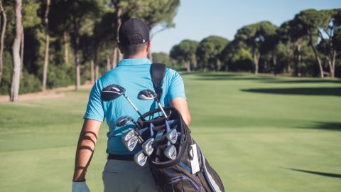 Man carrying golf bag while at golf course