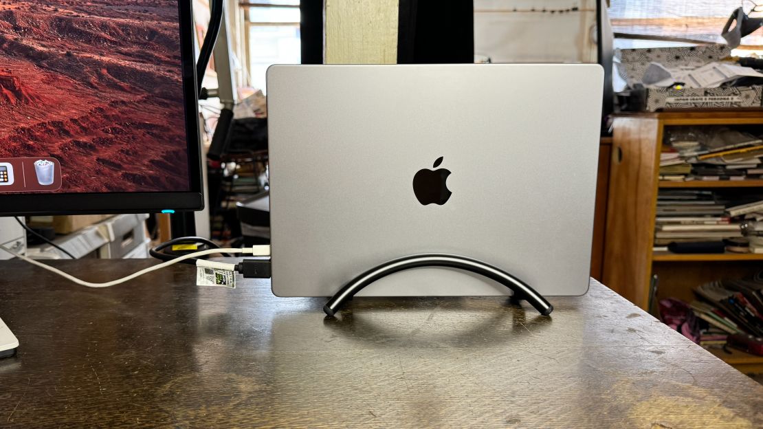 A MacBook stands upright in the black Twelve South BookArc Flex at a desk.