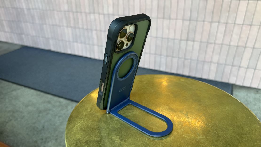 The Twelve South Curve Nano is attached to a phone in a green and black case, sitting on a gold-colored table.