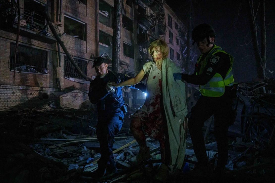 Agentes de Policía ayudan a una mujer herida a salir de su casa, dañada por un ataque aéreo ruso, en un barrio residencial de Kyiv, Ucrania, el jueves.