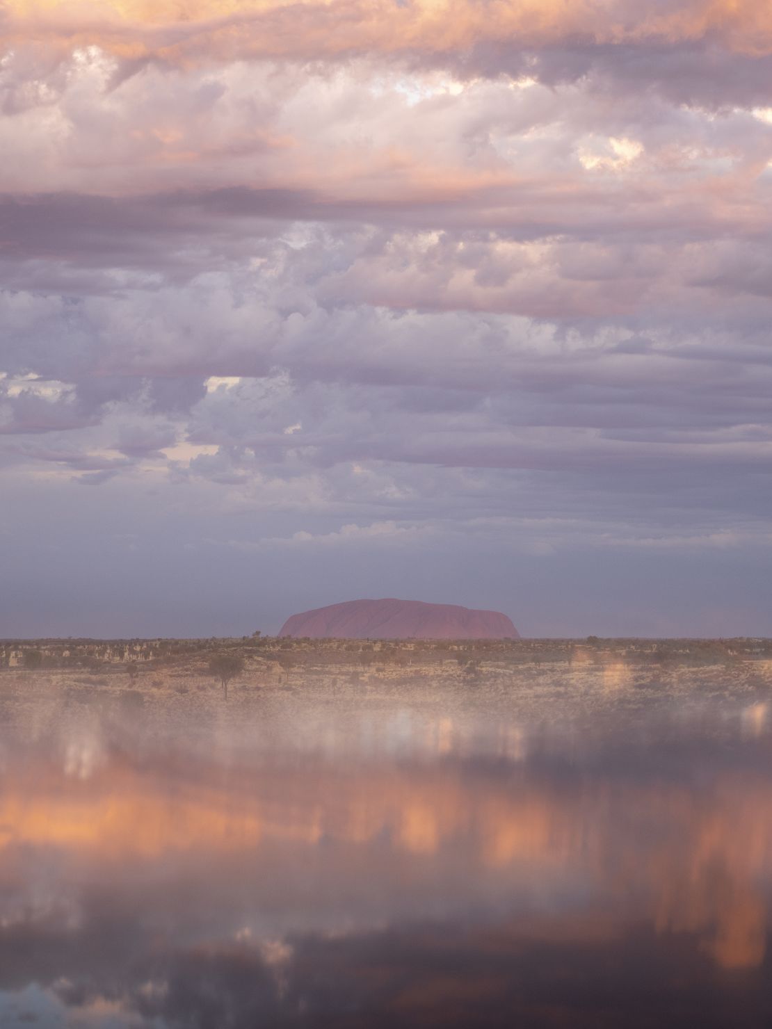 In this photo of Uluṟu, Burns uses a "reflective technique" to frame the sandstone monolith with the dusky sky.