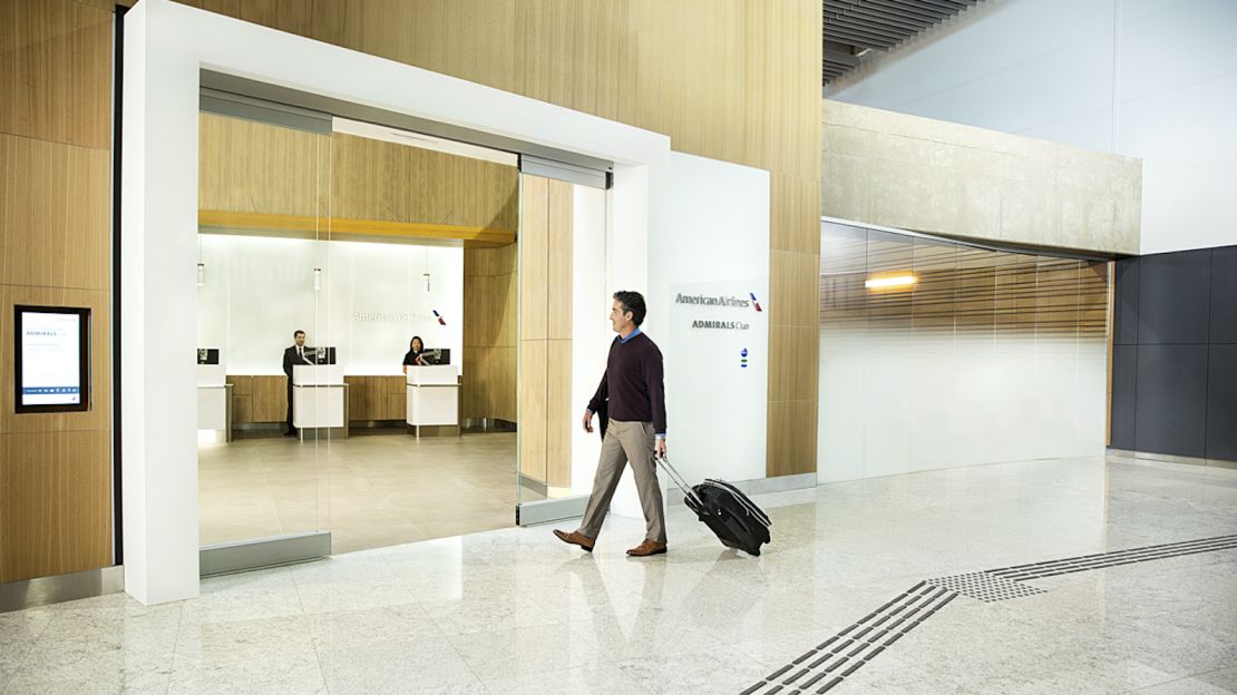 A photo of a person walking into an Admirals Club with their carry-on bag.