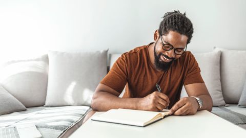 black man writing in budget book