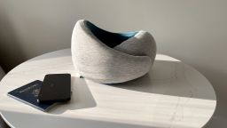 A photo of an Ostrichpillow Go travel neck pillow on a table next to a passport and an iPhone