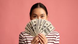 best cash back credit cards woman with cash in front of face