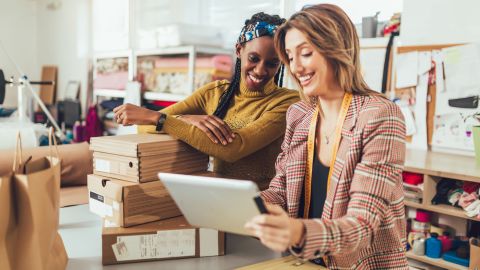 small business owners women with shipping boxes looking at tablet