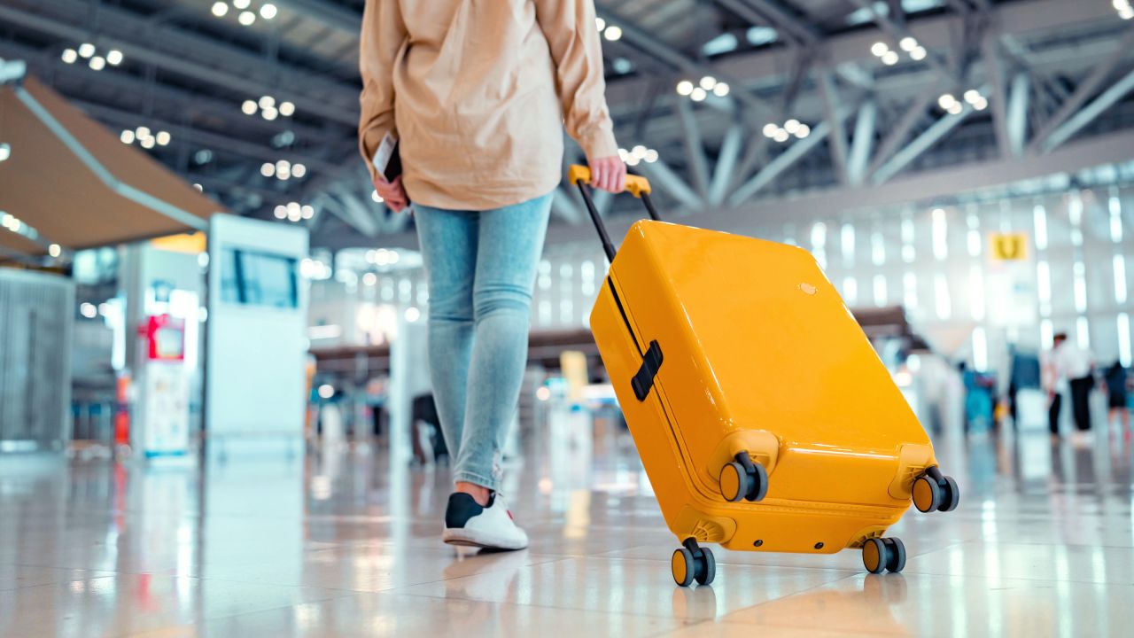 underscored travel week lead border Person walking through an airport terminal with a suitcase