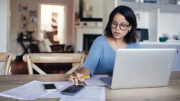 woman with calculator and laptop budgeting getting out of debt