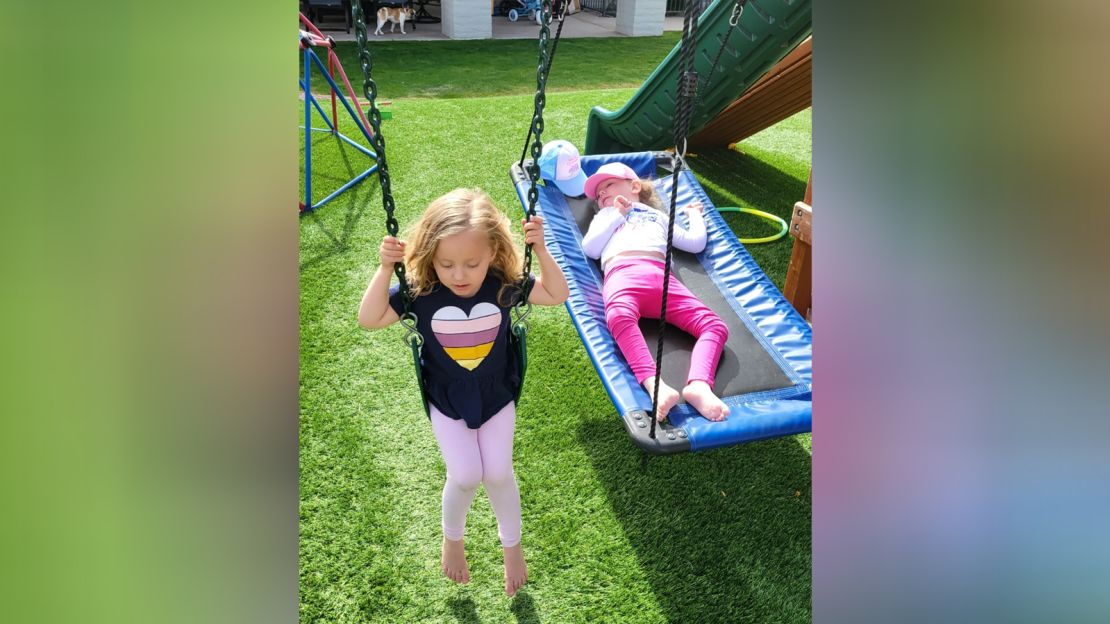 Keira and Olivia Riley at home in Phoenix.  The swing set in their backyard was given to Livvy after she requested it from the Make-A-Wish Foundation.  Courtesy of Kendra Riley