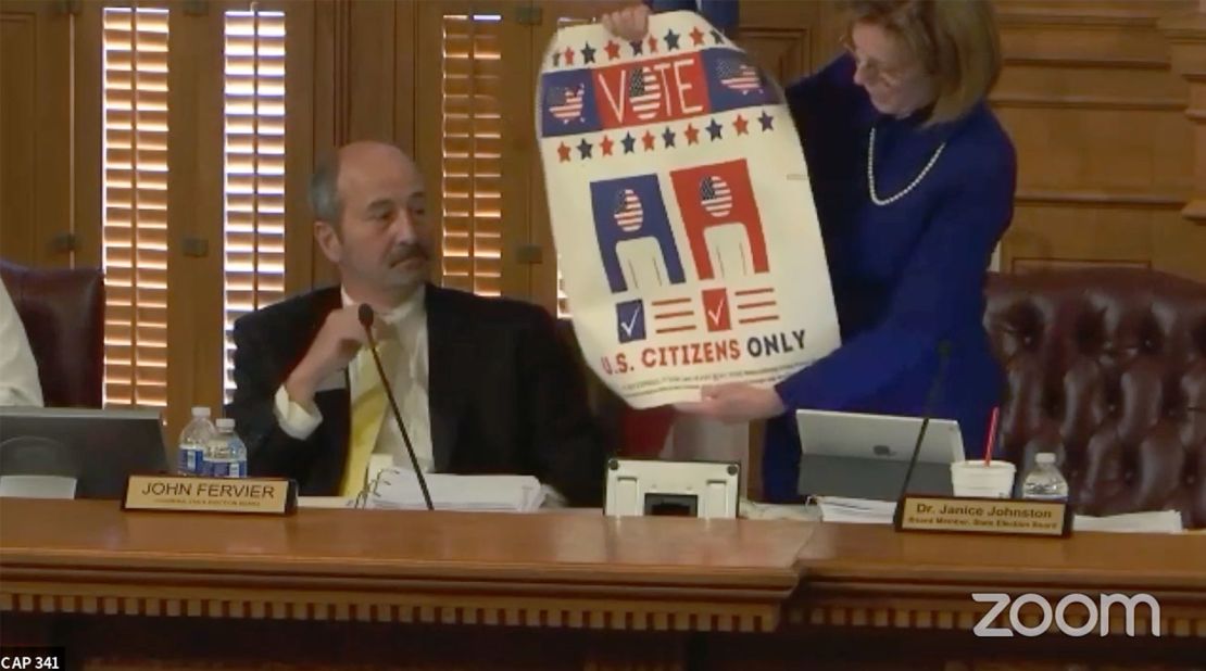 Dr. Janice Johnston holds up a sign during a board of elections meeting on August 6.