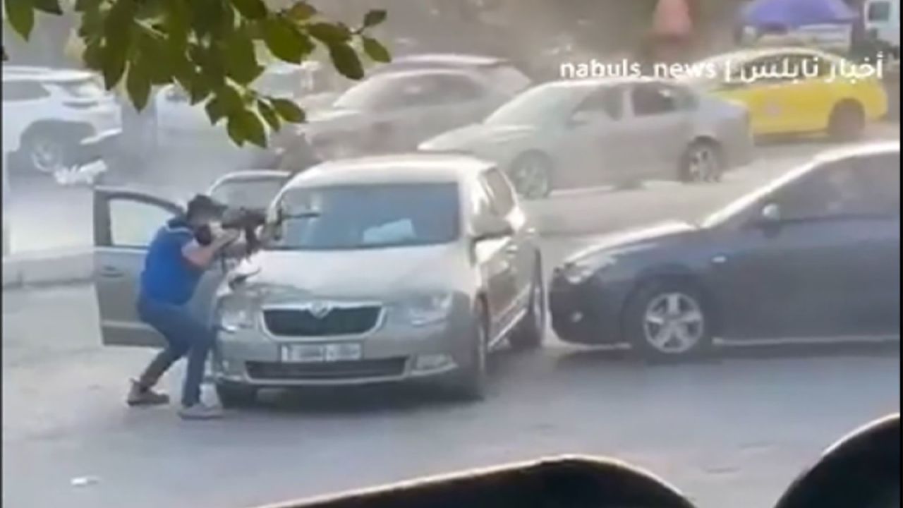 A video obtained by CNN shows at least four men standing behind a car while holding assault rifles and shooting at a second car across from them.